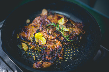 Cooked beef steak with rosemary and garlic inside iron skillet