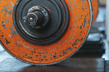 Old worn orange painted weight plates loaded onto a barbell