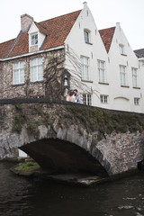 Fototapeta na wymiar Wedding photo shooting. Bride and bridegroom walking in Brugge. Stand on bridge and hug.