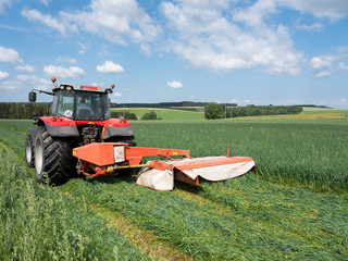 belgian farmer mows grass with tractor in field near Liege in the french part of belgium