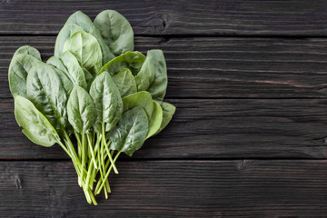 Fototapeta premium Fresh spinach leaves on wooden background. Natural, organic, healthy food. Vegetarian, dietary products. Copy space, top view. Horizontal orientation