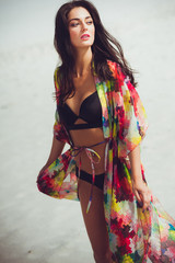 Portrait of young woman in colorful bikini on tropical beach looking at camera. Beautiful girl in...
