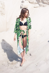 Beautiful young woman walking on the beach, green desert wear.