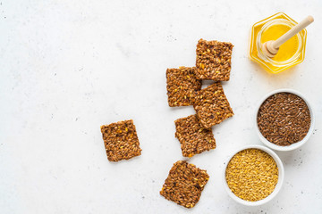 Golden and brown flax seeds and honey crackers on white stone background. Healthy raw vegan gluten free food concept.