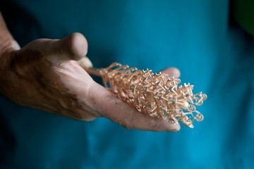 hands holding cast golden parts for jewelry