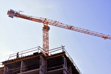 Fototapeta na wymiar Construction of a high-rise comfortable residential building with a reliable crane. Construction of buildings-architectural, organizational, survey, design, installation and commissioning of the objec