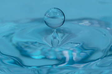 Fototapeta na wymiar Fallender Wassertropfen mit blauem Hintergrund