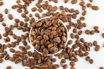 Roasted coffee beans in ceramic bowl on white, close-up, top view