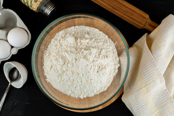 Making dough for pizza, flour in glass bowl on wooden cutting board