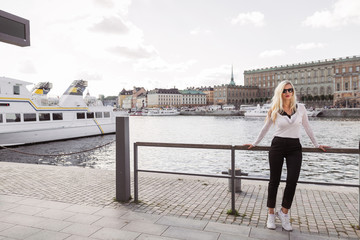 The young beautiful woman standing against the background of river and city