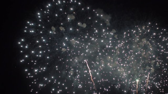 Brilliant fireworks display, patterns and starbursts explode in dark night sky