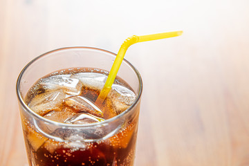 Icy cold beverage in a glass, close-up view. Glass of cool fizzy drink with ice on a wood table, detailed shot