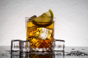 Whiskey glass with ice cubes and lemon slice. Alcohol shot beverage.