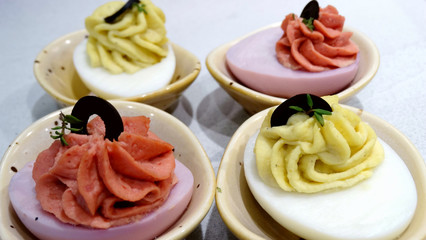 Colorful deviled eggs with sliced bitter chocolate and fresh rosemary green leaves decoration....