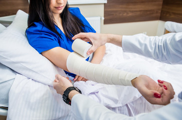 Male doctor bandaging hand of female patients.