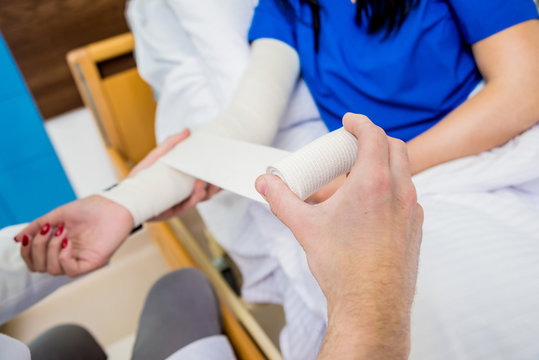 Male doctor bandaging hand of female patients.