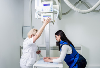 Radiologist and patient in a x-ray room. X-ray of human hand. Classic ceiling-mounted x-ray system.