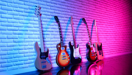 several electric guitars against a brick wall in neon light, 3d illustration - obrazy, fototapety, plakaty