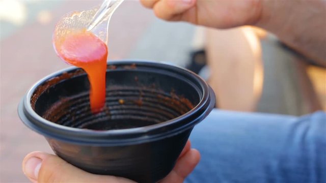 Cold gazpacho soup. The red liquid falls down the spoon. Outdoor, real time, warm, summer, hot, close up