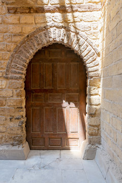 Vaulted closed wooden grunge door in bricks stone wall