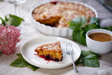 Blackcurrant cake with almond topping and a cup of coffee