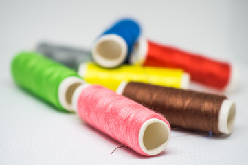 Multi-colored spools of cotton threads for sewing on a white background close-up