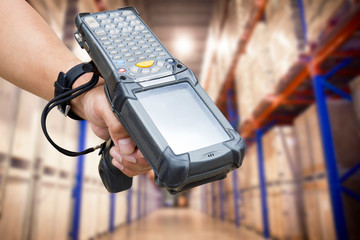 close up hand of worker holding barcode scanner with warehouse background. - obrazy, fototapety, plakaty