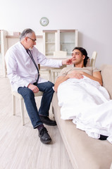 Old male doctor visiting young male patient  