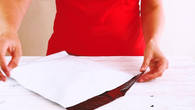 Woman closing self adhesive poly envelope, package, good wrapping