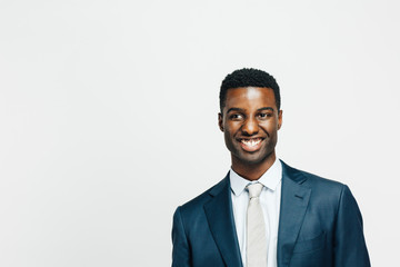Portrait of a smiling, happy man in suit and tie looking to the side, isolated on white studio background