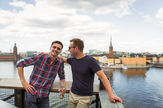 Portrait of the smiling young friends who are standing against the background of the city and sea and talking