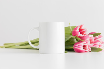 Mug mockup with bouquet of pink tulips on a white table.