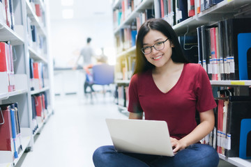 Fototapeta premium Portrait of young Asian woman with computer laptop in library,Education Concept.