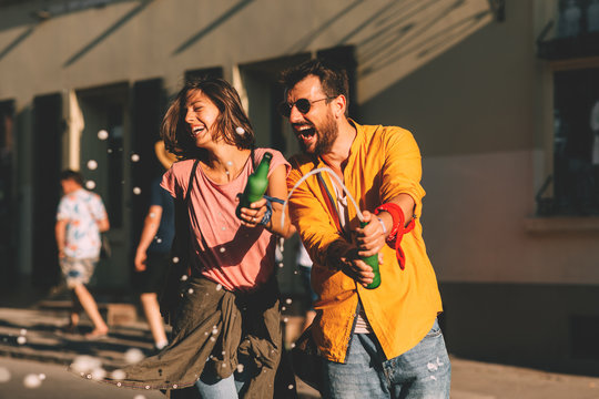 Young couple dancing on the street and holding two bottles of beer