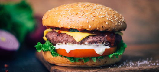 Home made Burger (cheeseburger) with beef on a wooden background. Classic home made Burger. Close up, copy space.