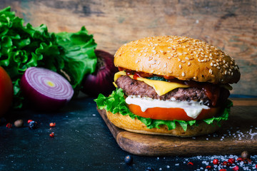Home made Burger (cheeseburger) with beef on a wooden background. Classic home made Burger. Close up, copy space.