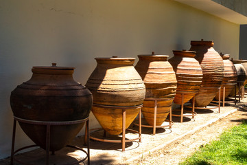 Huge earthenware jugs exhibited in the sun outside. Old pottery pots outside. Old orange clay jugs.
