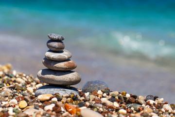 Fototapeta na wymiar Pyramid of stones on pebble beach near the ocean. Obo from pebbles. Stone tower on the beach. Balance, peace of mind.