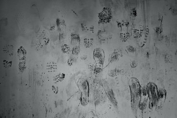 Black footprint on white wall background. An interesting background created as a result of hooliganism in the public space. - obrazy, fototapety, plakaty