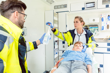 Emergency doctor and paramedic giving infusion in ambulance © Kzenon