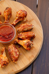 Spicy deep fried chicken wings and legs with dipping sauce on wooden plate , wood background.