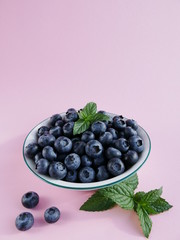 Bowl of blueberries in front of light pink background