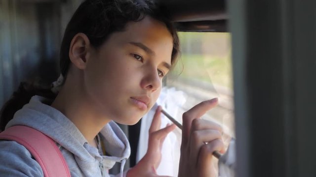sad girl looks out the train window. travel transportation railroad concept. teen girl misses lifestyle traveling in a train compartment looking out the window. long train journey by rail