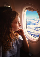 young girl looks out the window in a passenger plane