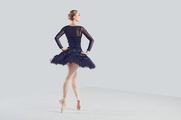 Ballerina in a black tutu elegantly dancing on a black background.