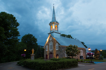 Side view of pretty small 1859 stone Saint-Felix-de-Valois church in the Cap-Rouge area of Quebec City during a cloudy summer evening, Quebec, Canada
