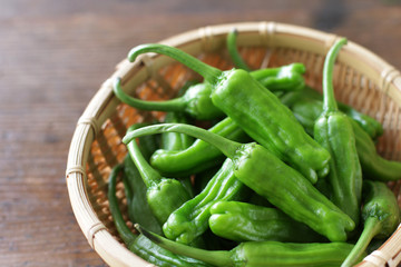 木目板背景の緑の夏野菜のししとう