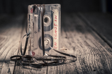 One cassette tape with an extracted tape on wooden table