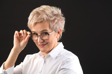 beautiful elderly woman in a white shirt and glasses on a black background