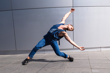 Young man dancing on street with arms outstretched